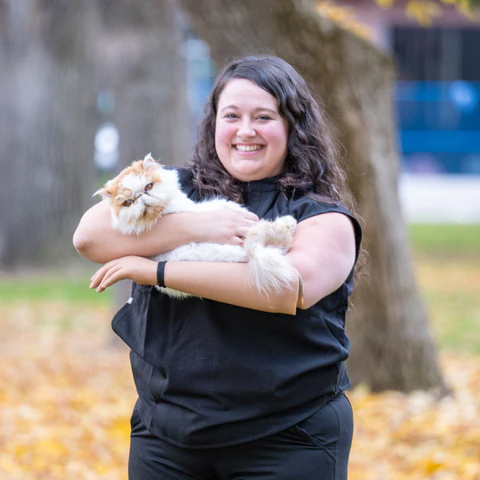 Veterinary Technician Assistant Graduate, Alexandra Starker smiling while holding a cute cat.