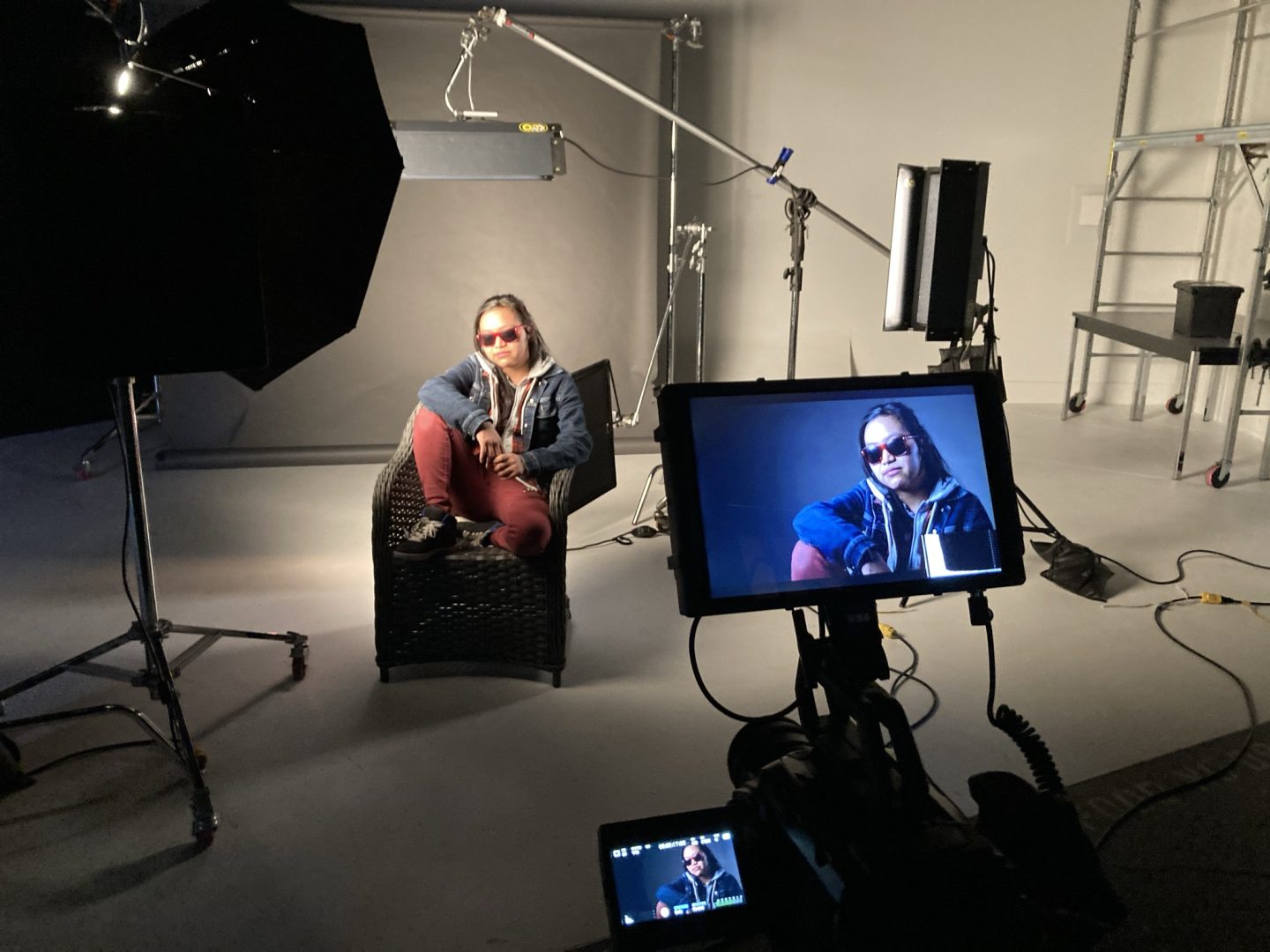 Informative image portraying Acting for Film and Television students, featuring a woman seated on a chair in front of a camera. This snapshot captures the essence of practical learning and creative exploration within the dynamic environment of the College for Arts and Design.