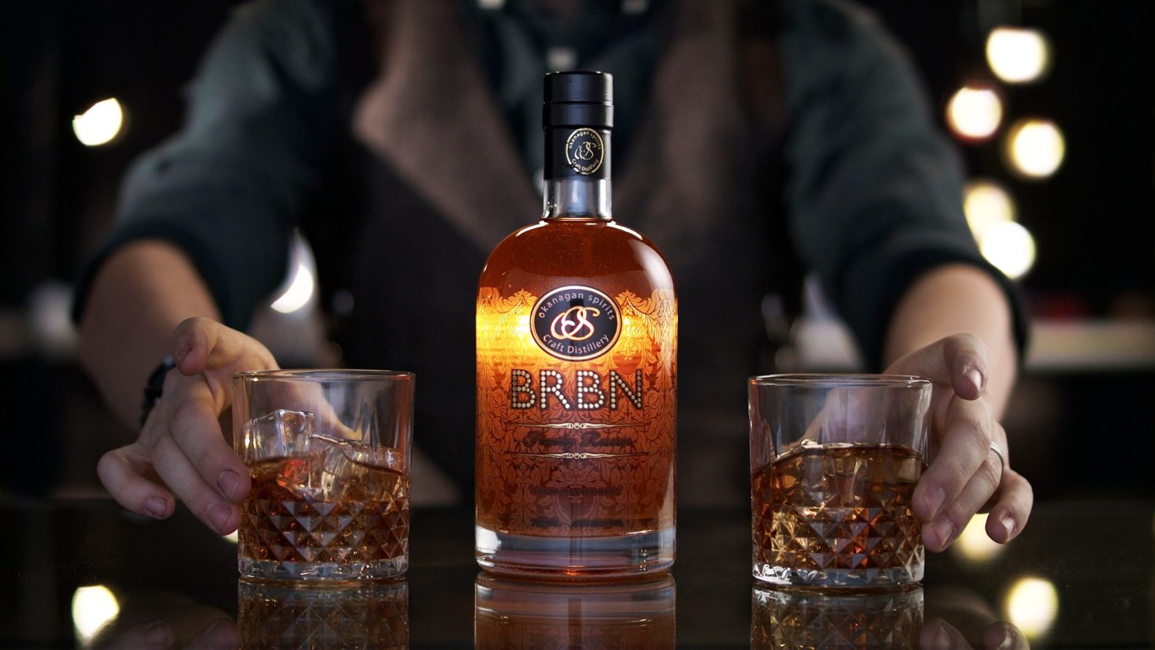 BRBN Whiskey bottle with 2 glasses being served on bar by bartender.